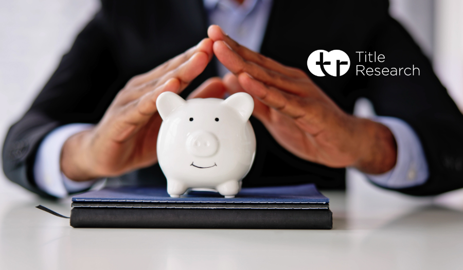 Man in a suit holding hands over a white piggy bank on a table.