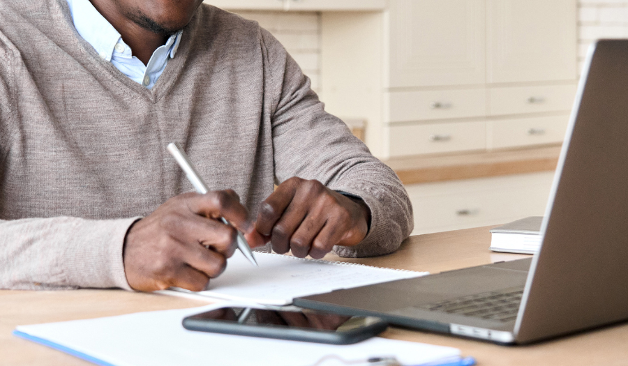 Man at desk with notes and laptop