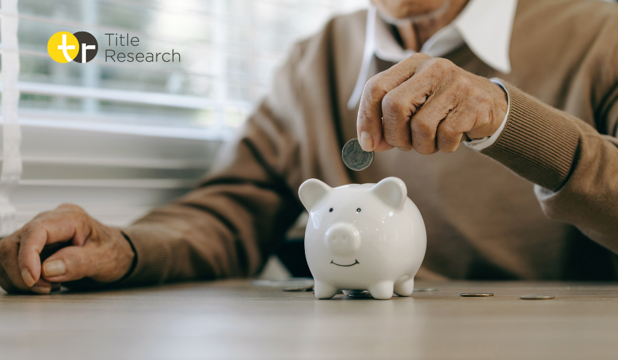 An elderly person putting money into a piggy bank