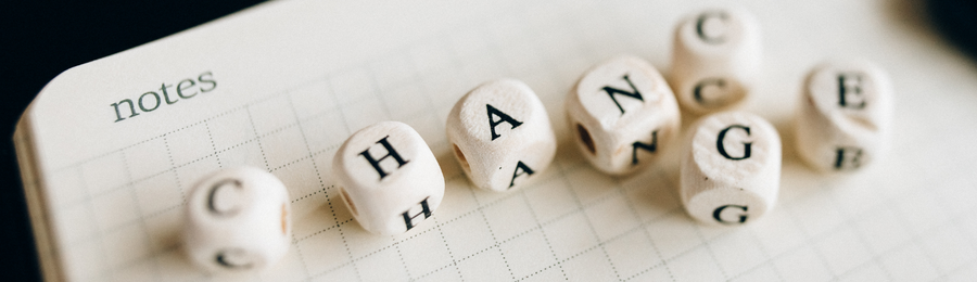 Lettered dice spelling "change" on a notepad