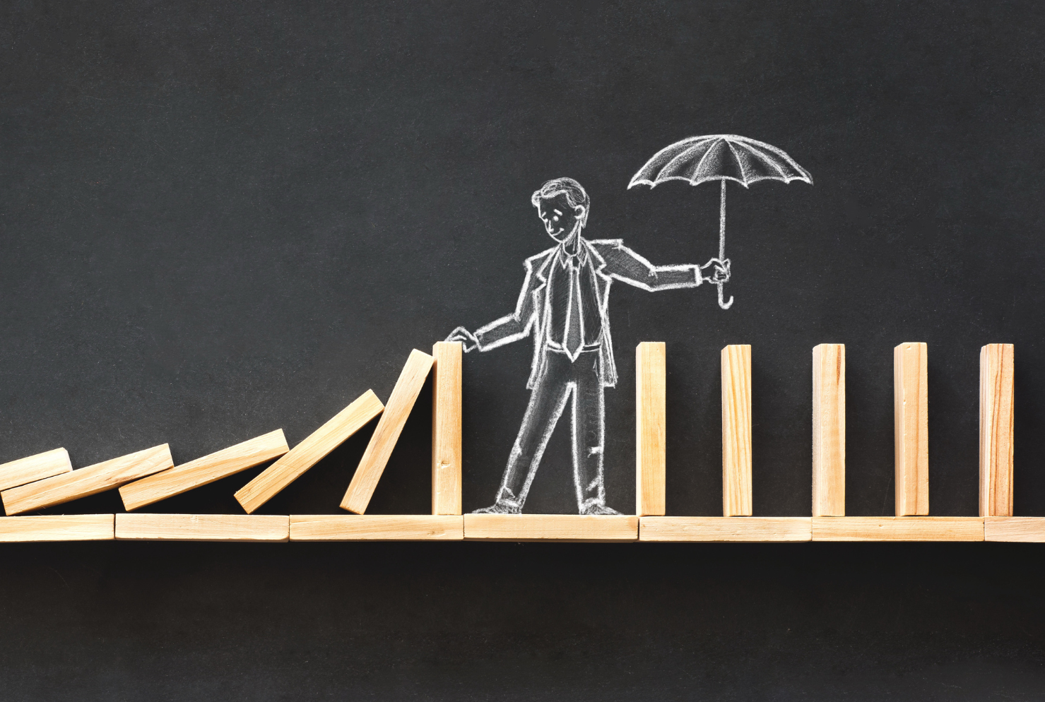 Chalkboard man stopping dominoes from falling