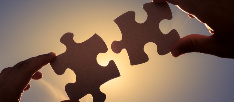 Hands joining two puzzle pieces